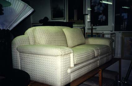  Sofa en tissu damassé blanc posé sur une table en bois.