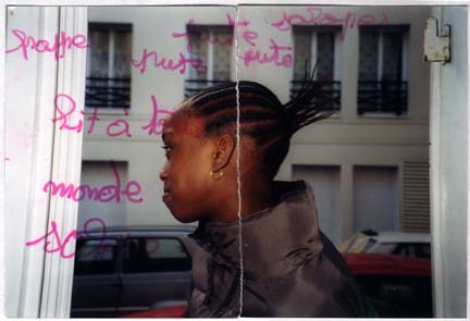 Petite fille noire de profil dans l'embrasure d'une fenêtre. Image avec traces écrites au feutre rose.