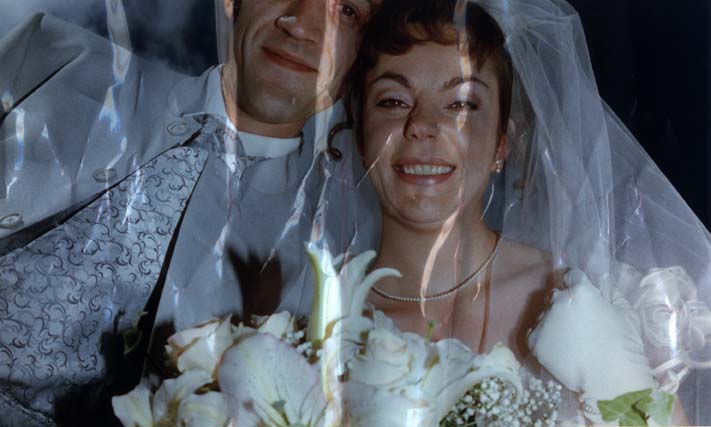  Couple de mariés souriant avec bouquet de fleurs. Image avec froissure.