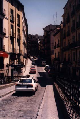  Voiture blanche au passage d'une passerelle face à une rue en montée. 