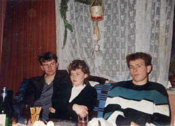  Deux hommes et une femme assis sur une banquette face à une table avec bouteilles et verres.