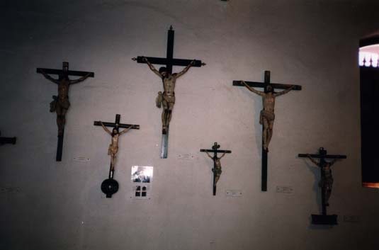  Grands et petits crucifix en bois avec Christ accrochés à un mur blanc.